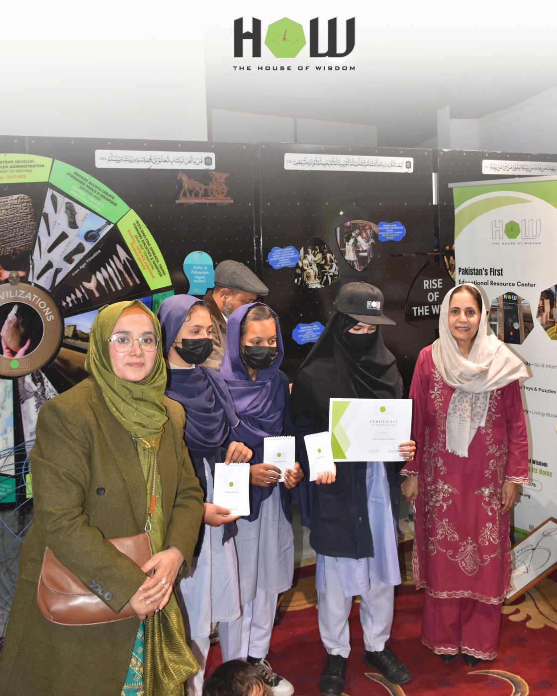 House of Wisdom learners and team members standing beside exhibition displays
