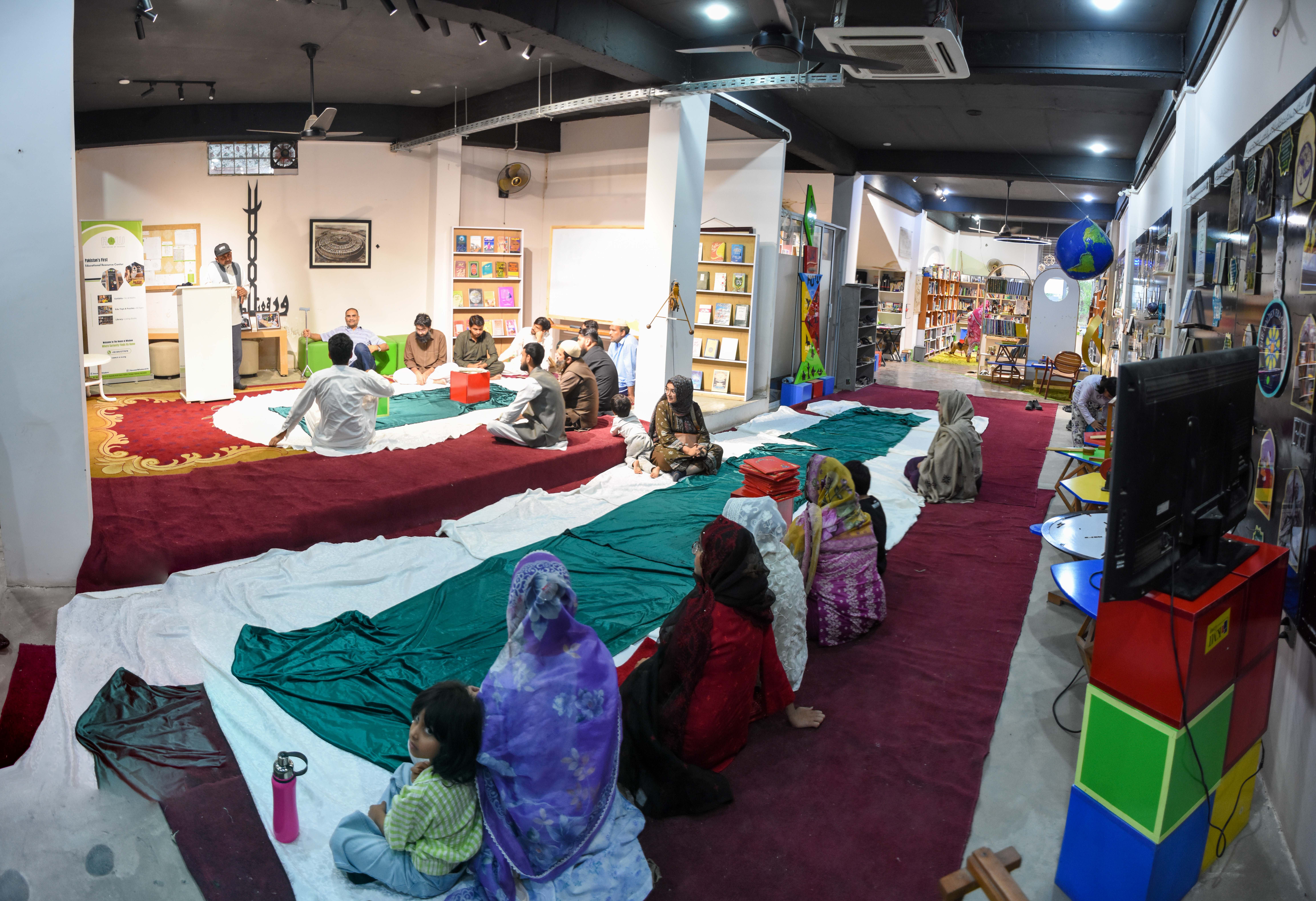 Family Reflection — A mother and young child sit peacefully near the back, part of the wider family gathering absorbed in reflection and dua.