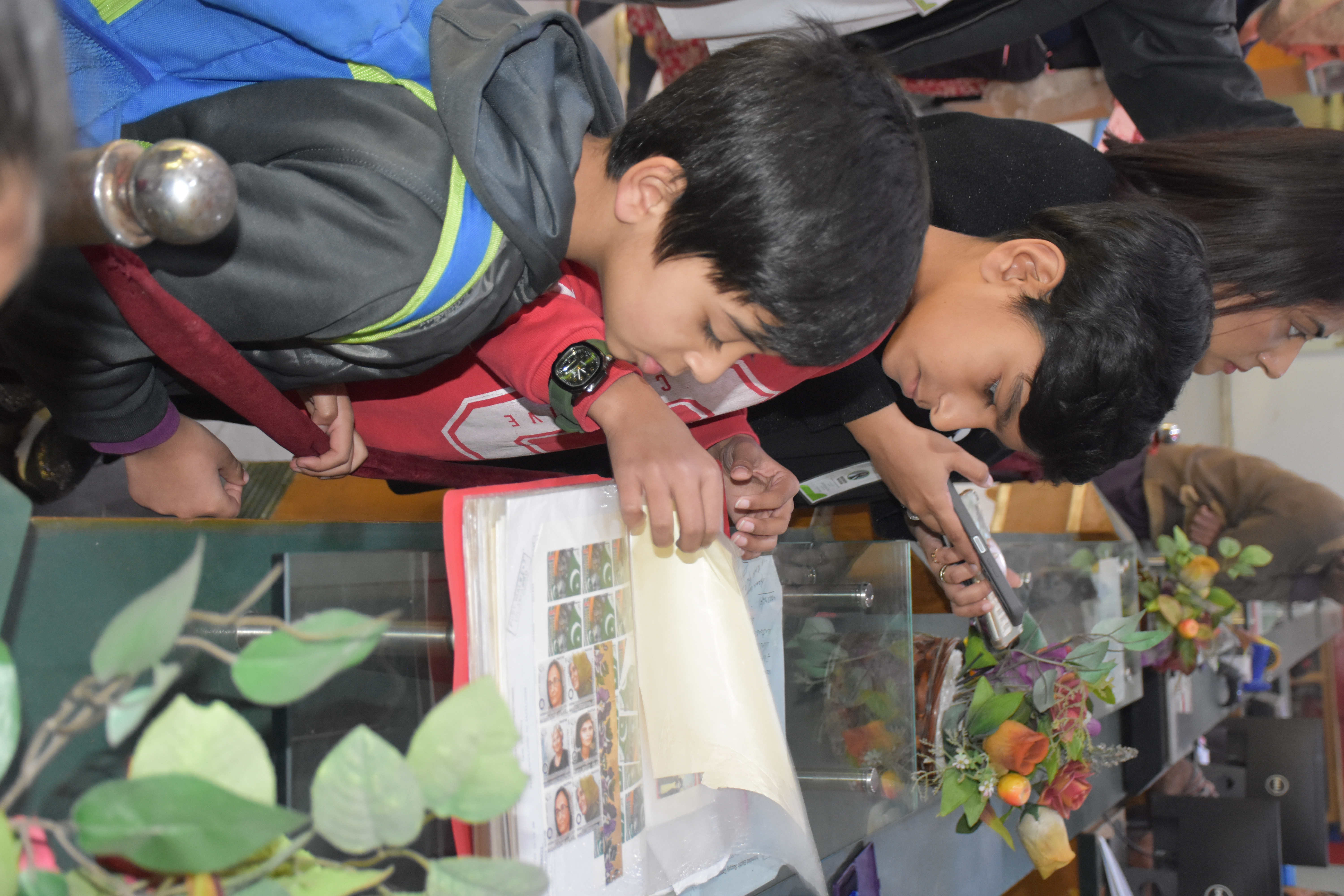 Discovery — Students carefully leaf through a stamp album, discovering the artistry behind everyday mail.
